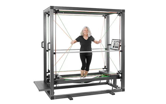 Eine Frau steht im Sensopro, einem Trainingsgerät mit Rahmen und Seilen, und hält sich locker an den Seilen fest.